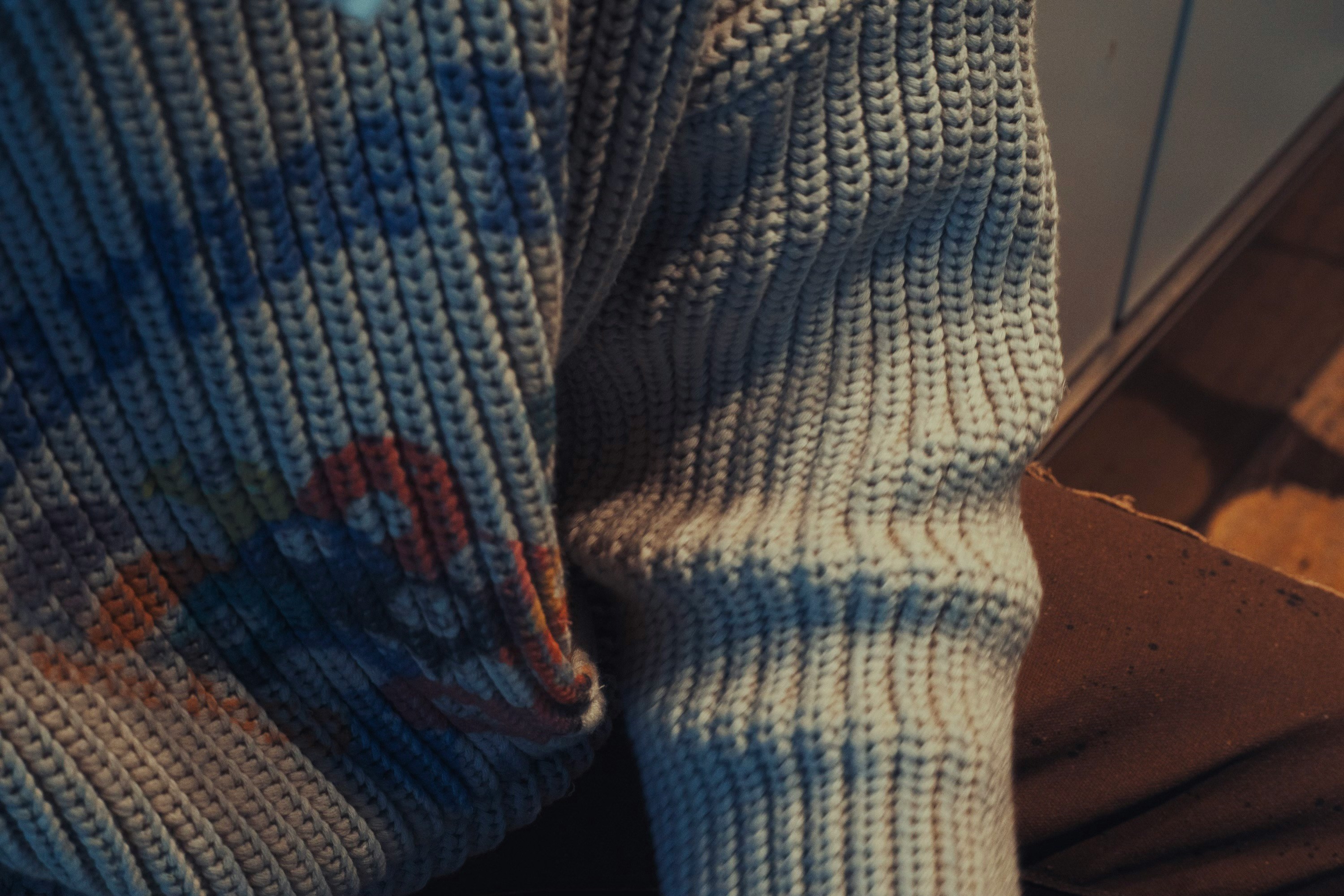 Close-up of two ribbed sweaters showing stitch density and multi-colour yarn work from an EETHEN production run